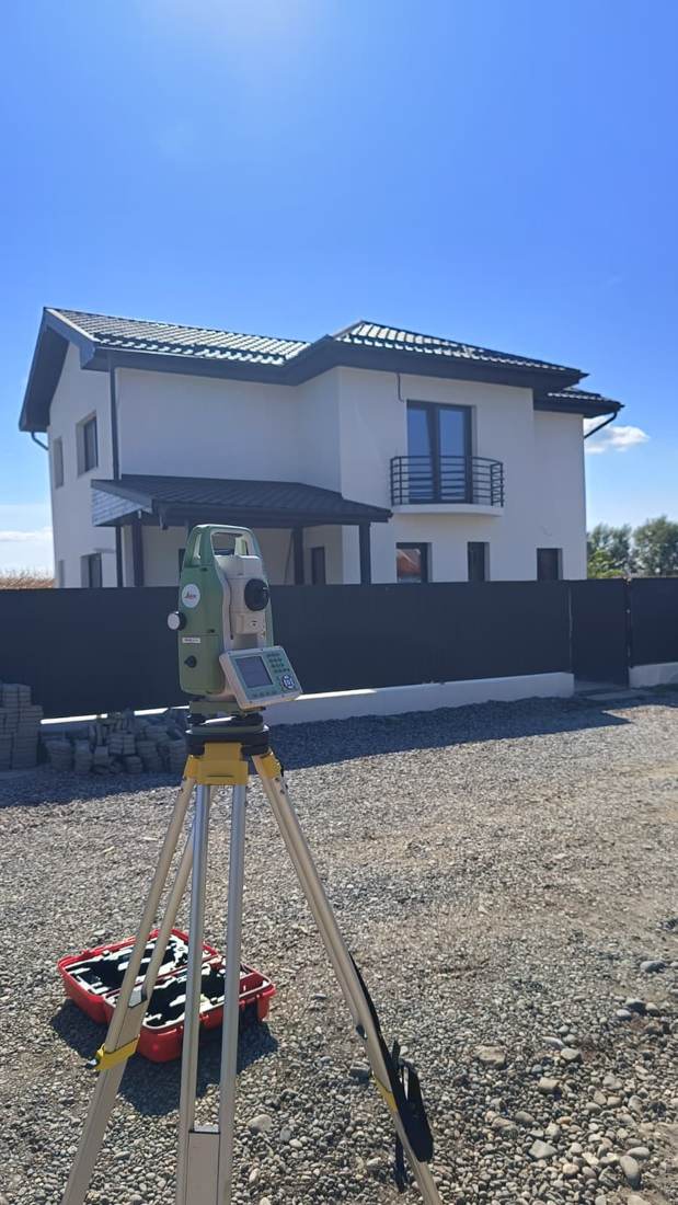 Stație totală Leica în fața unei case noi, înainte de recepția lucrării.